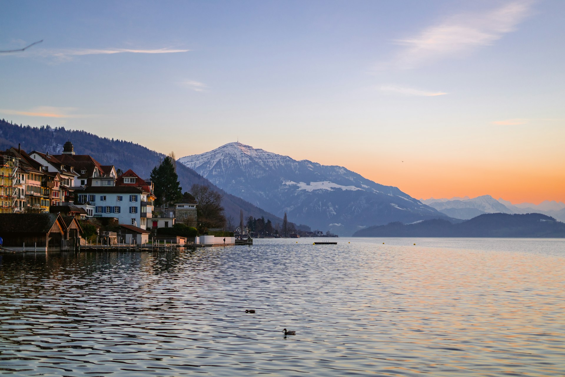 a body of water with houses and mountains in the background